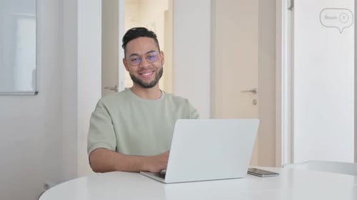 Man working at laptop smiles at the camera