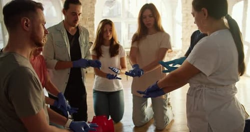 Closeup Shooting A Processional Nurse in a White Uniform Teaching a Group of People to Fold Their