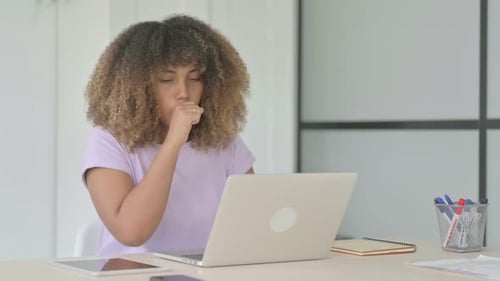 Young Woman Coughing While Working on Laptop