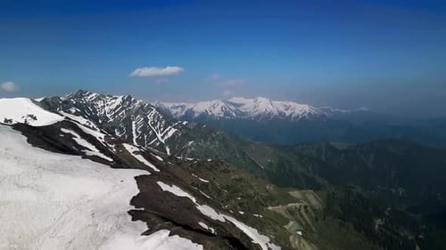 Aerial view of large and white snow covered Tibetan mountains during a sunny day. Steep slopes.