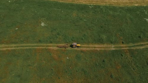 Traktor mit Heuzetter fährt auf einer Landstraße zwischen Wiesen, nachdem er Futter für Kühe vorbereitet hat