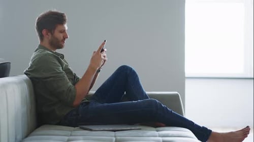 Man Relaxing on Couch with Smartphone