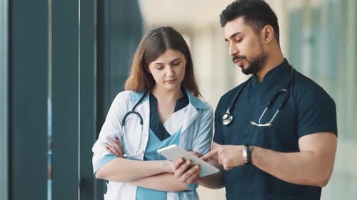 portrait A doctor and a nurse are talking in a hospital corridor with a tablet