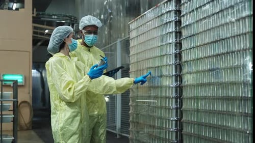 Deux superviseurs inspectent la qualité des contenants utilisés dans la fabrication d'aliments en conserve.
