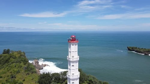 Aerial drone footage of Baron beach in Yogyakarta, Indonesia with lighthouse and traditional boats.