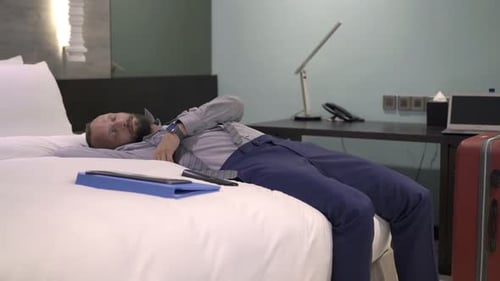 Tired Businessman Sleeping On Bed In Hotel Room At Night