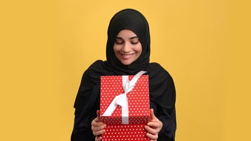Portrait Oriental Woman Open Festive Gift Box with Astonished Emotion Isolated on Orange Studio