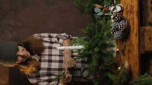 Woman Decorates Christmas Tree with Pinecones
