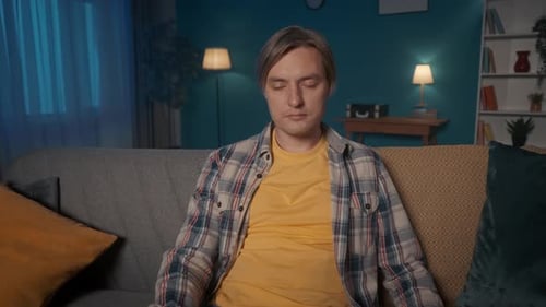 Sleepy Tired Man Watching TV While Sitting on the Couch Late at Night A Man Falls Asleep with a