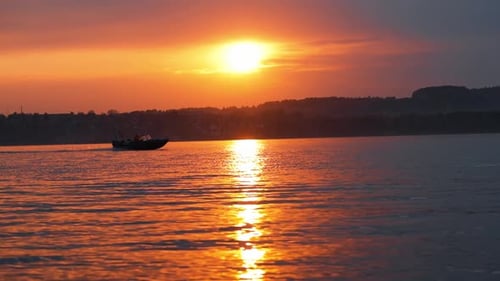 Gorgeous Orange Sunset Casting Its Reflection on the Serene Water As a Fishing Boat Glides Across