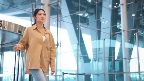 Felicidade: mulher asiática sorridente, passageira caminhando com uma mala amarela, bagagem no terminal do aeroporto