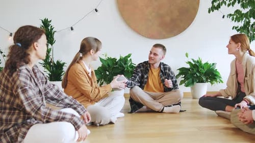 A Circle of Multiracial People Share Insights and Experiences in a Cozy Plantfilled Setting During a