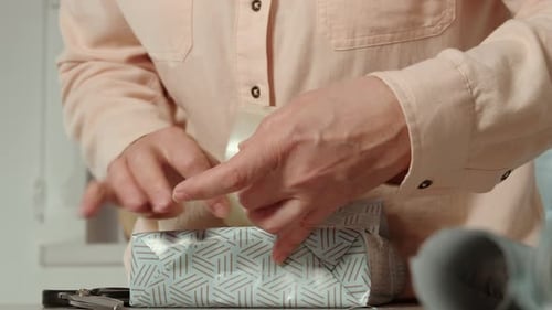 Wrapping Gift with Tape on Table Indoors