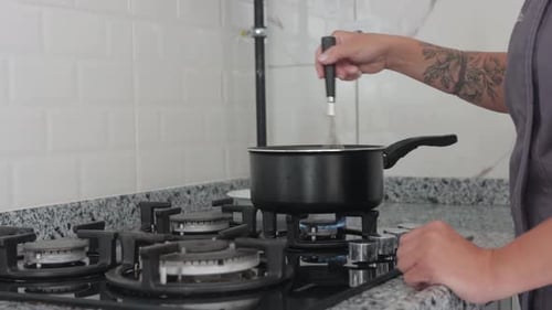 Woman Stirring Saucepan on Gas Stove