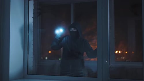 Masked Figure Enters Dark Building Through Window