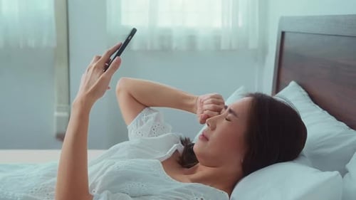 Woman Uses Phone While Lying in Bed