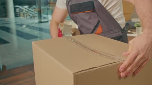 CloseUp of Employee Worker Sealing Cardboard Box Using Duct Tape Machine