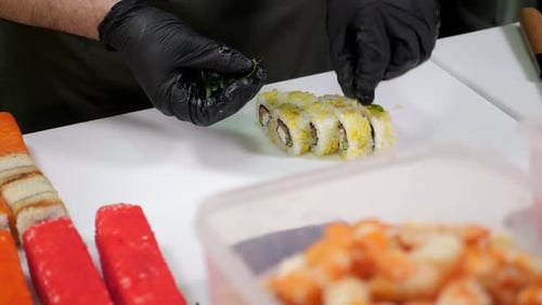 Closeup of a Chef Putting Green Chili Peppers on Sliced Sushi in a Restaurant