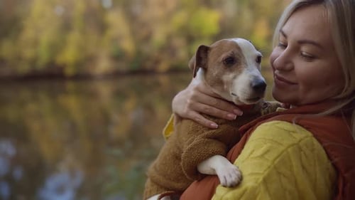 Portrait of a Smiling Young Woman Kissing a Dog in a Field