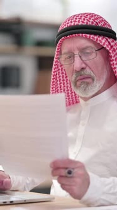 Senior Man Reviews Documents at Office Desk