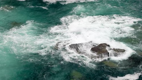 Aerial View of Waves Crashing on Rocky Shore