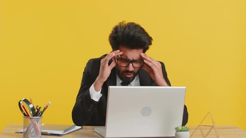 Stressed Man Working at Laptop in Office
