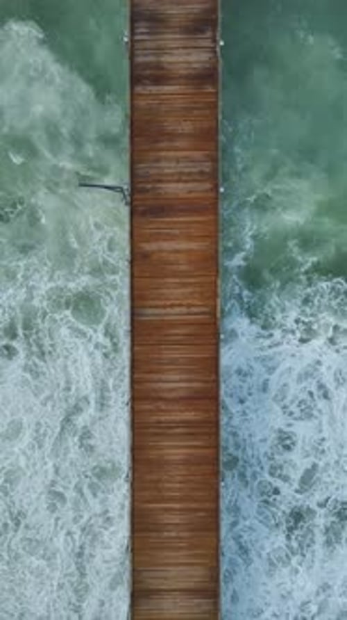 Vertikales Video eines hölzernen Piers mit Blue Sea Motion und Sonnenschirmen an warmen Sommertagen