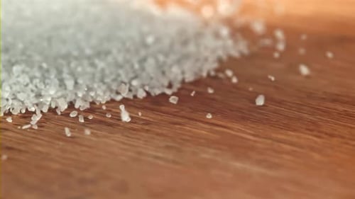 Sea Salt Pours onto Wooden Surface in Macro Shot