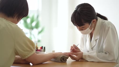 Manicurist Performing Nail Care on Customer