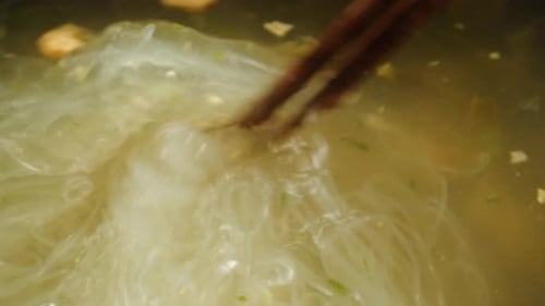 Clear Noodles lifted with Chopsticks from Warm Soup