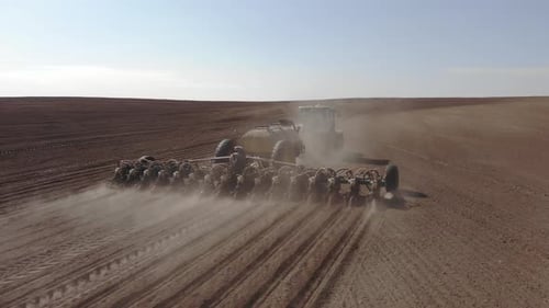 Green tractor planting sunflower on the sandy field in Ukraine 4K