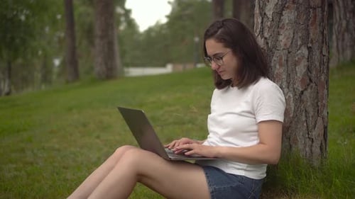 Young Woman Working on Laptop in a Park