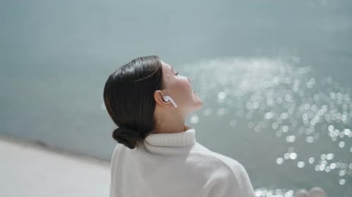 Carefree Young Woman Putting Face Under Sunlight Sitting on Waterfront Alone Closeup