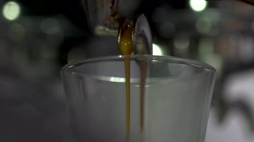 Macro close up of a cafe coffee machine, coffee shot pouring into a glass (4K)