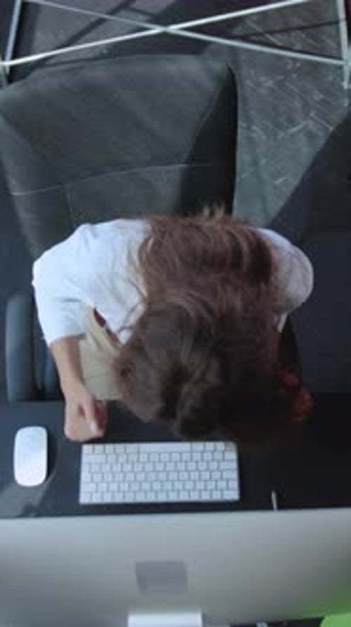 A Professional Woman Sitting at Her Desk Typing Efficiently in a Modern Office Environment