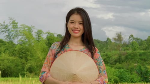 Vietnamese farm woman stand in rice field plantation with bamboo hat smiling in camera