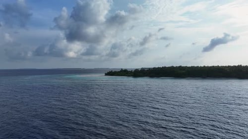 Aerial view of an uninhabited island with green trees in the morning, Maldives.