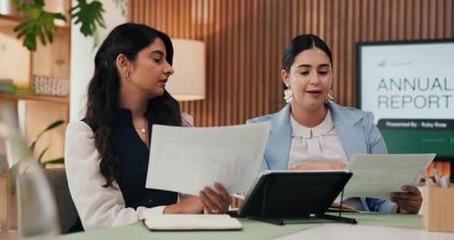 Two Women Reviewing Annual Report in Office Setting