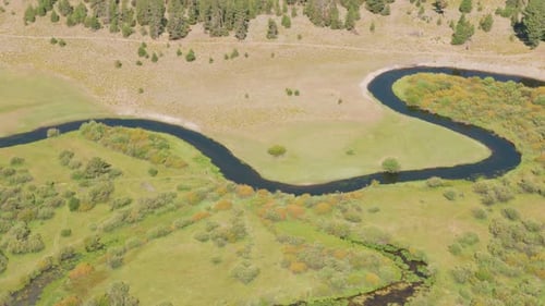 Aerial View Of A Winding River Flowing Through Green Meadows