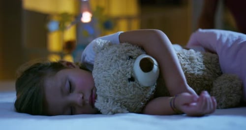 Child Sleeping Peacefully with Teddy Bear in Bed