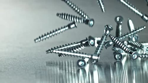Metal Fasteners Scattered on Reflective Table with Motion and Shine Filmed on a Highspeed Camera at