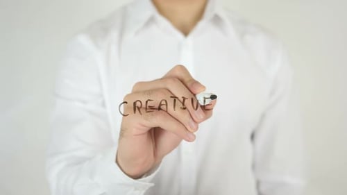 Man writes 'Creative' on clear surface