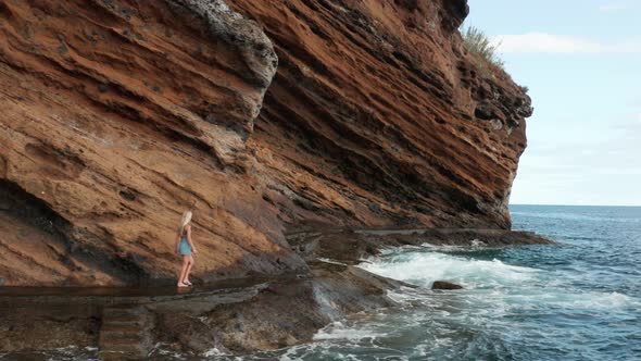 Adventure girl walks on slippery pathway at rugged cliffs with waves of ...