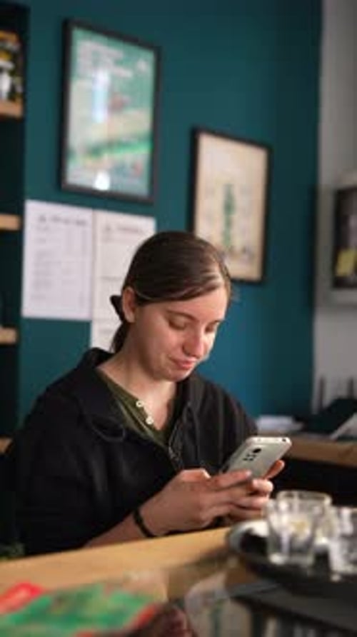 Woman in Cafe Reads and Browses on Smartphone Engaged in Digital Communication and Social Media