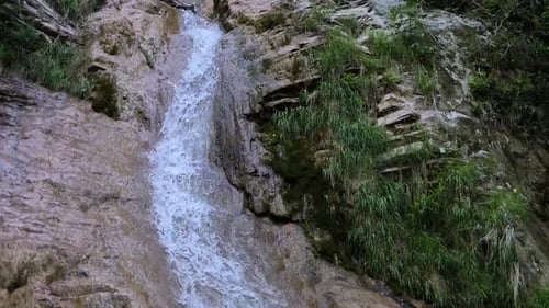Closeup of a Waterfall in the Mountains Among Green Bushes and Trees
