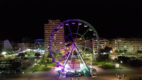 Ferris Wheel Turns in Colorful City at Night