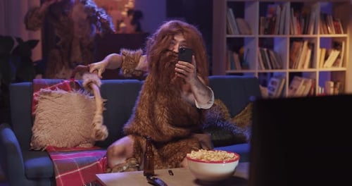 Wild Bearded Man in Animal Savage Fur Taking Selfie Picture on Smartphone Camera Interacting