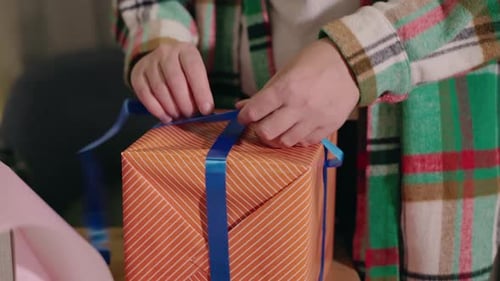 Tying Blue Ribbon on Orange Birthday Gift