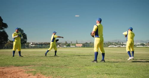 Checking ball in glove prompting four male teammates tossing ball across outfield under clear sky