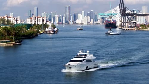 Yacht cruises from Miami harbor on a sunny summer day aerial drone view